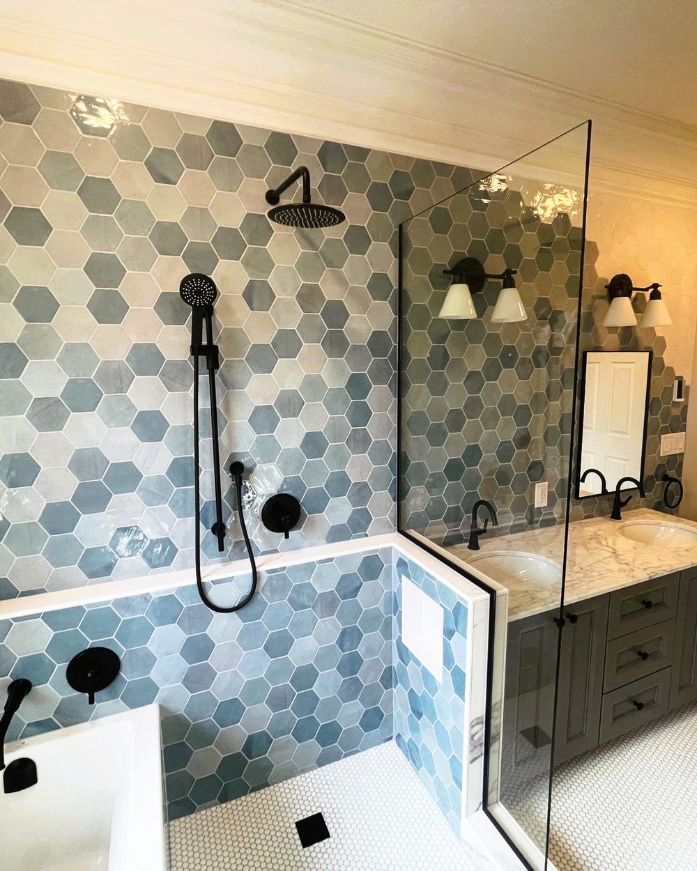 Finished wet-room ensuite by Lions Group: blue hex tile, rain shower and double vanity behind glass