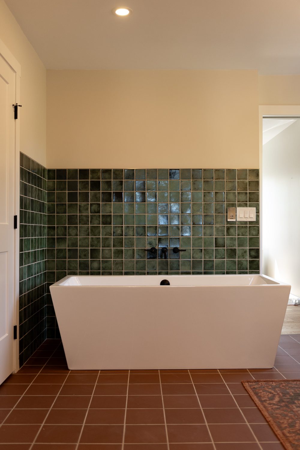 Finished ensuite by Lions Group: freestanding tub against a green zellige tile wall with terracotta floor