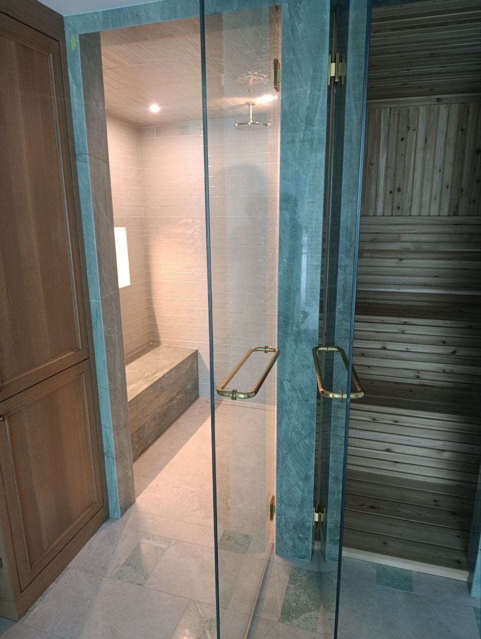 Finished spa bathroom by Lions Group: glass shower beside a cedar sauna with stone columns